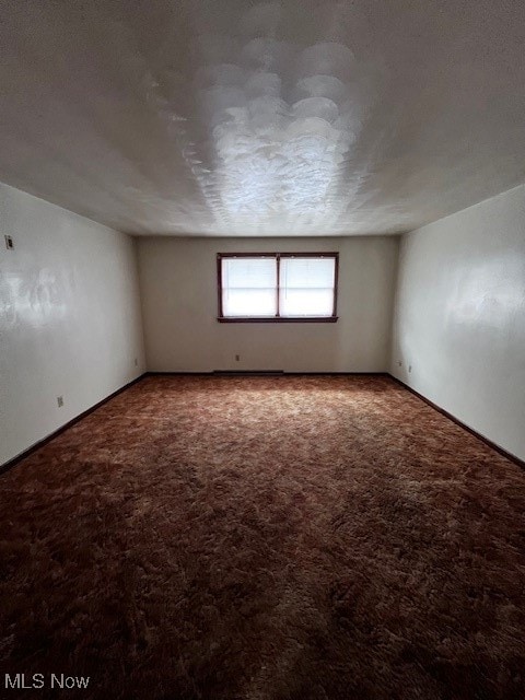 Carpeted empty room featuring a textured ceiling
