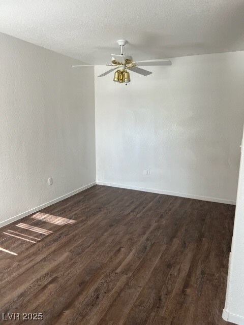 Empty room with a ceiling fan, baseboards, and dar