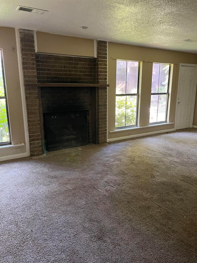 Unfurnished living room featuring a brick fireplac