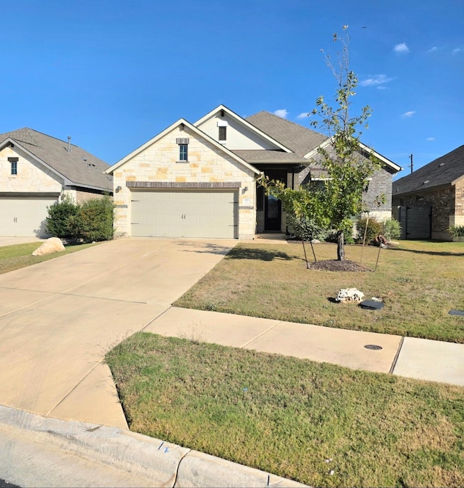 View of front of house featuring a front yard, concrete driveway, an attached garage, and brick siding