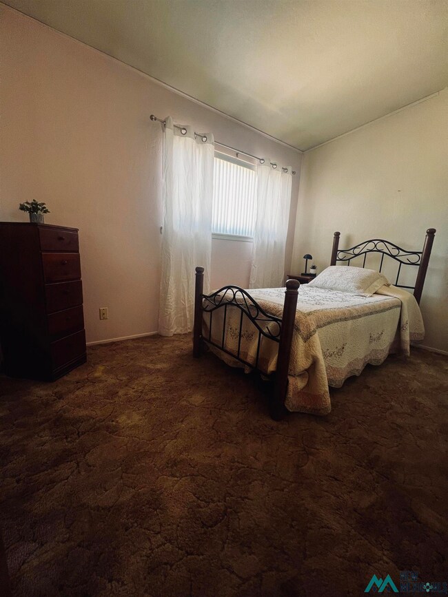 Bedroom with dark carpet and baseboards