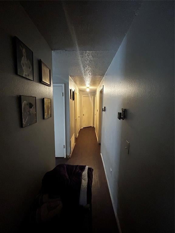 Hallway with baseboards and a textured ceiling