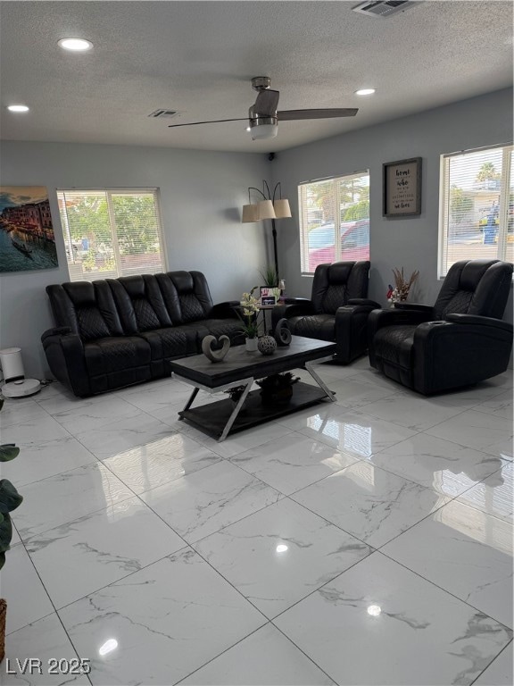 Living room featuring light marble finish flooring, a textured ceiling, healthy amount of natural light, ceiling fan, and recessed lighting