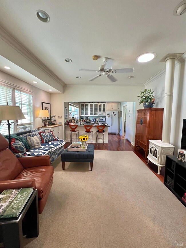 Unit 102 is a three-bedroom residence. Pictured here is the living room, as currently arranged by the tenant, featuring rich Brazilian cherry floors and a charming electric wood-burning stove.