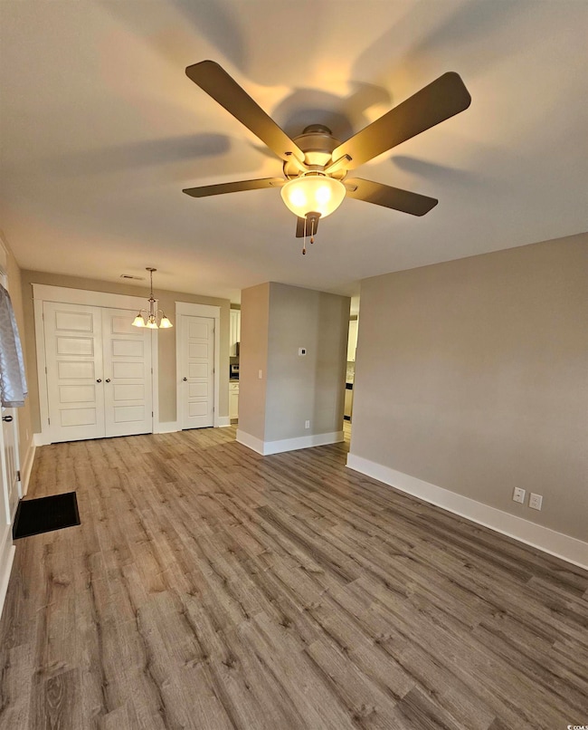 Unfurnished room with wood finished floors and a chandelier