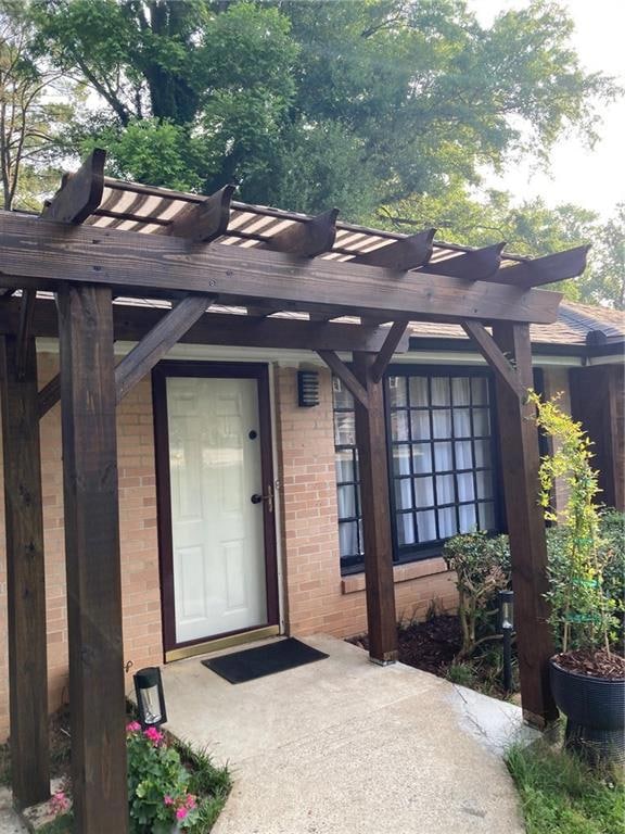 Entrance to property with a pergola and brick siding