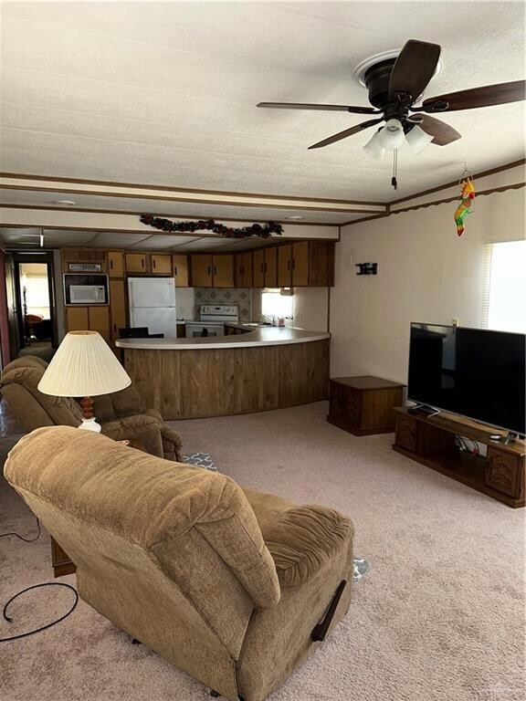 Living area with light carpet and a ceiling fan