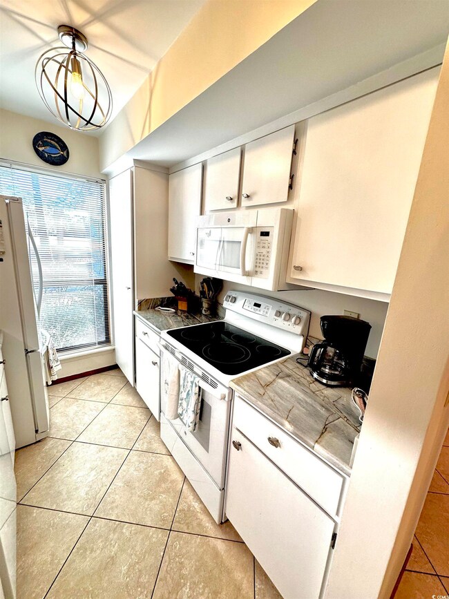 Kitchen with light tile patterned floors, white ap