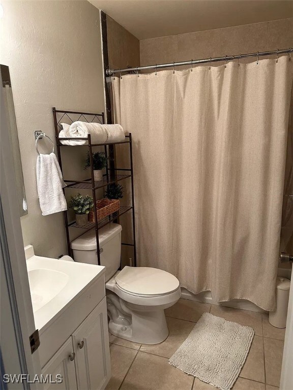 Bathroom with toilet, tile patterned floors, vanit