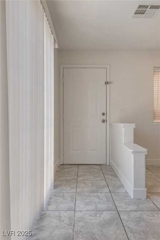 Hallway with light marble finish floors and basebo