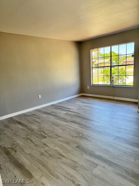 Spare room featuring a textured ceiling, wood fini