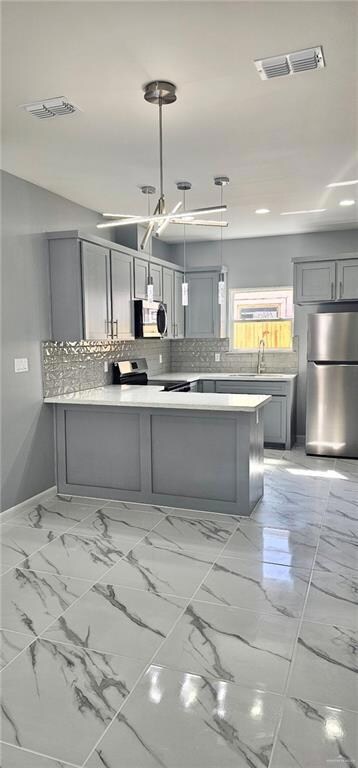 Kitchen featuring appliances with stainless steel finishes, gray cabinetry, light countertops, light marble finish flooring, and recessed lighting