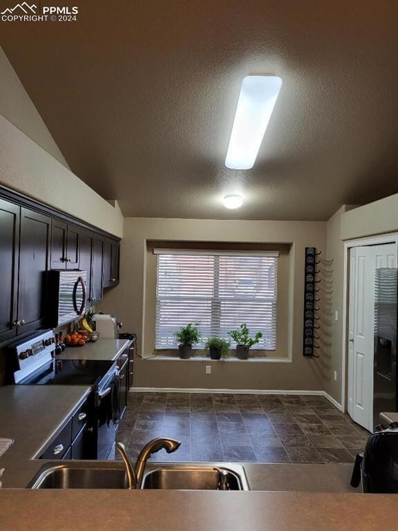 Kitchen featuring vaulted ceiling, dark tile floor