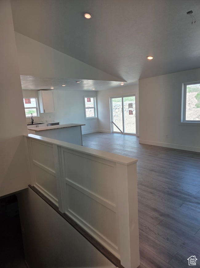 Kitchen with white cabinetry, wood finished floors, recessed lighting, baseboards, and open floor plan