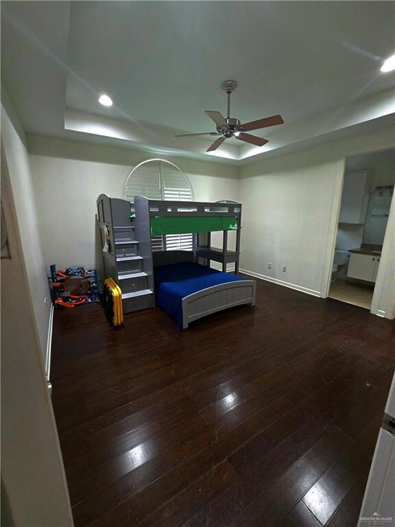 Bedroom with a tray ceiling, dark wood-type flooring, recessed lighting, and ceiling fan