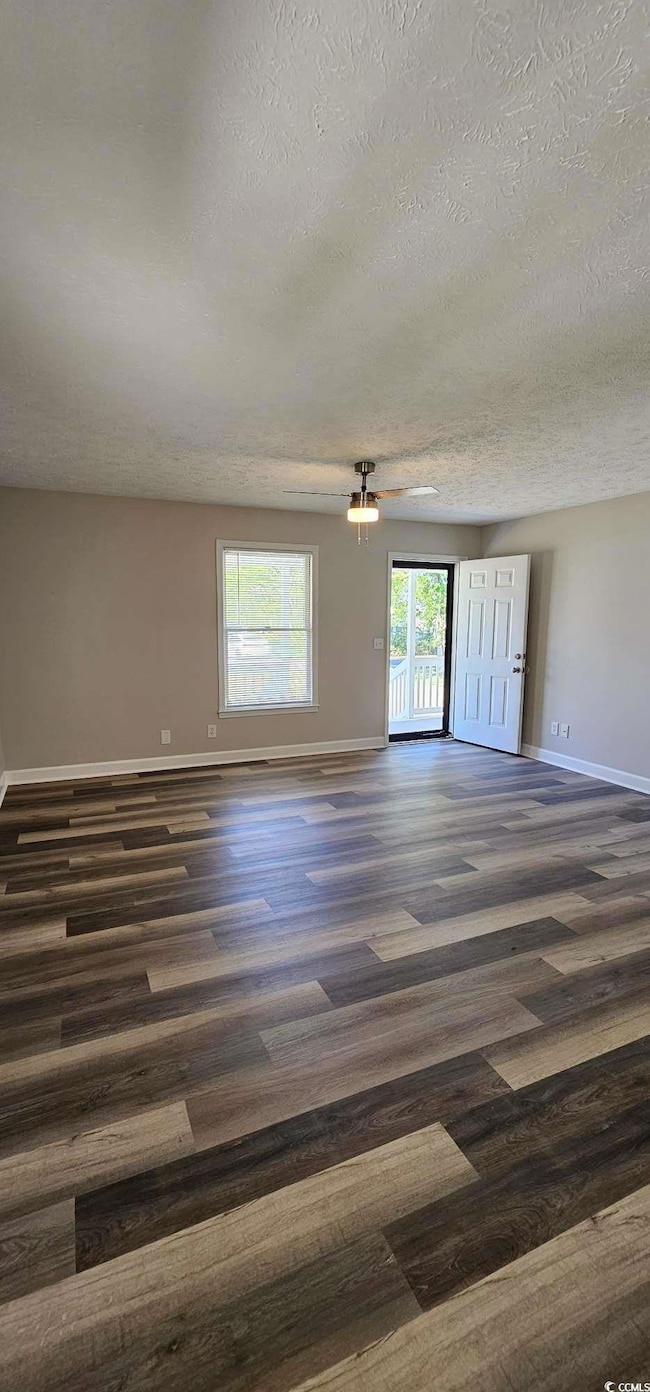 Unfurnished room with a textured ceiling and dark wood-style flooring