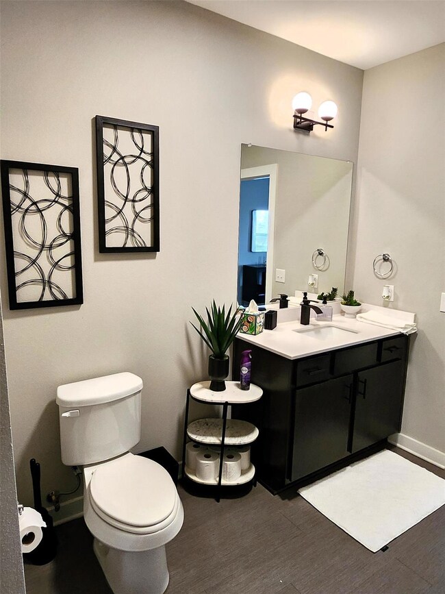 Half bathroom with toilet, baseboards, wood finis