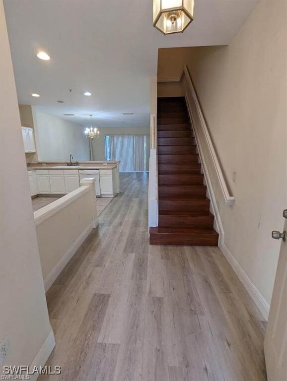 Staircase featuring wood-type flooring and a notable chandelier
