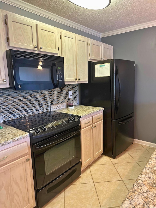 Kitchen featuring black appliances, crown molding, textured ceiling, light tile  floors, and light cabinetry