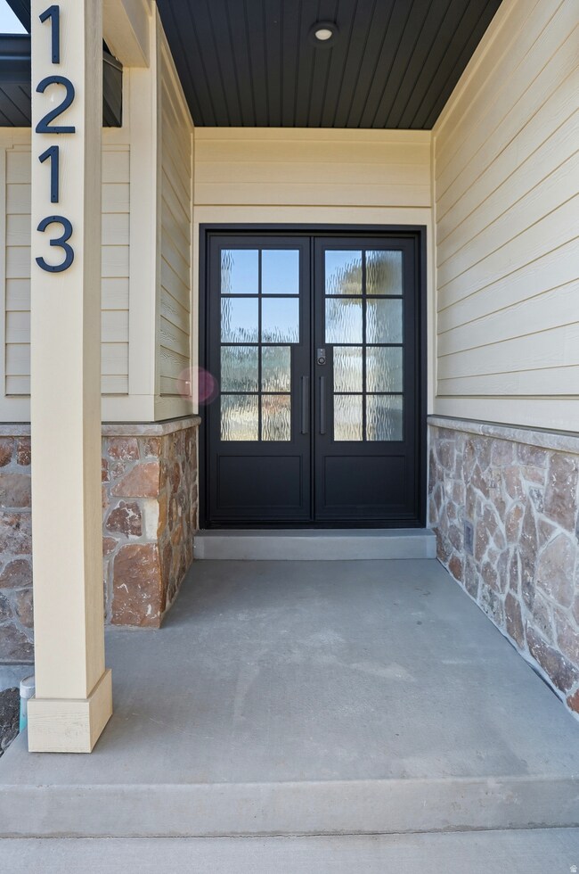 View of exterior entry featuring stone siding and french doors