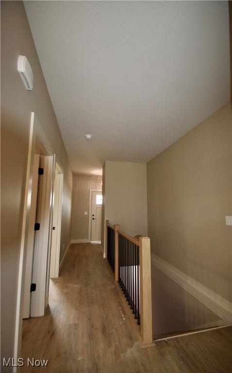 Corridor with wood finished floors and an upstairs landing
