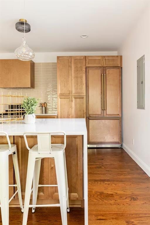 Kitchen featuring pendant lighting, dark wood-type flooring, electric panel, and a kitchen bar