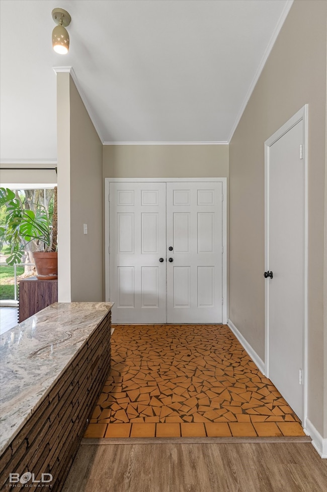 Entryway featuring wood finished floors and crown molding