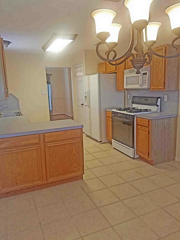 View of the Kitchen from the Breakfast room showing gas stove, pantry and refrigerator.  Opening to Formal Dining Room.