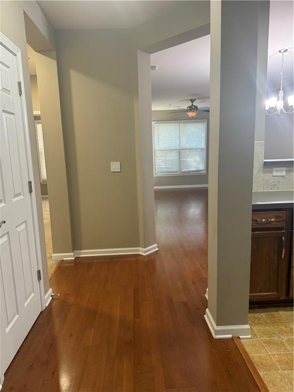 Hallway featuring dark wood-style flooring and a chandelier