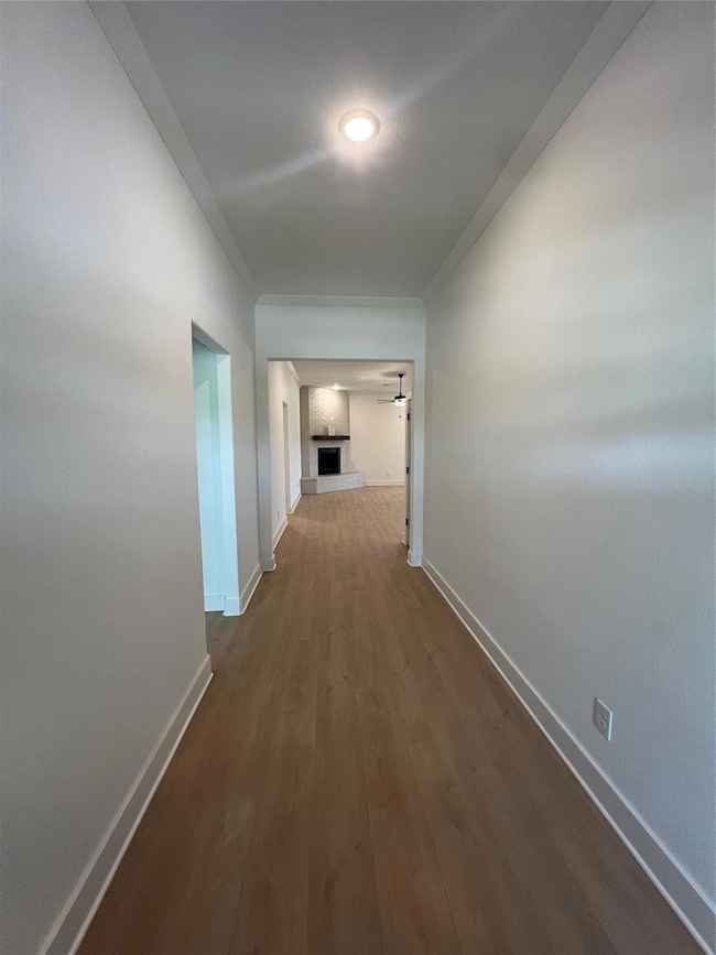 Hallway with baseboards, crown molding, and dark w