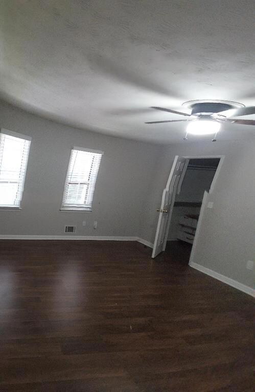 Spare room featuring baseboards and dark wood-type flooring