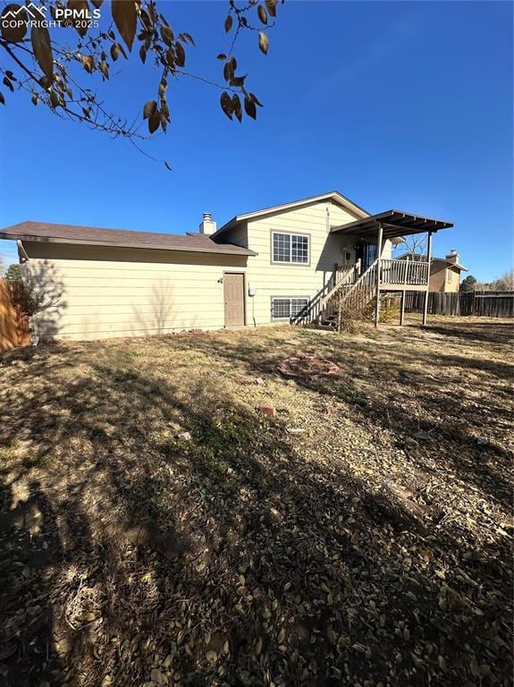 Back of house with stairs, a chimney, and a wooden deck
