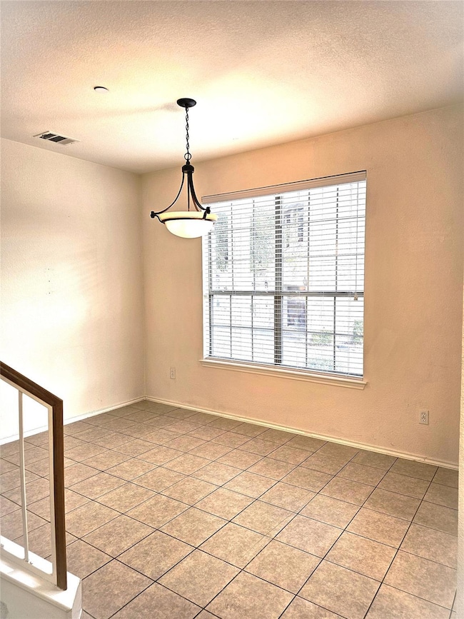 Unfurnished room with a textured ceiling and light tile patterned floors