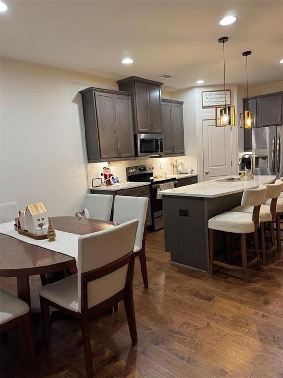 Kitchen featuring a kitchen island with sink, dark