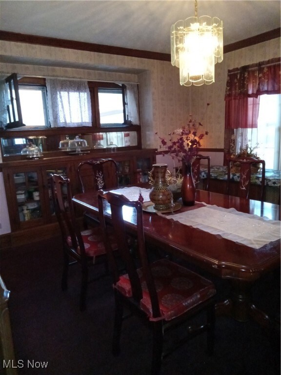 Dining area with ornamental molding and a chandelier