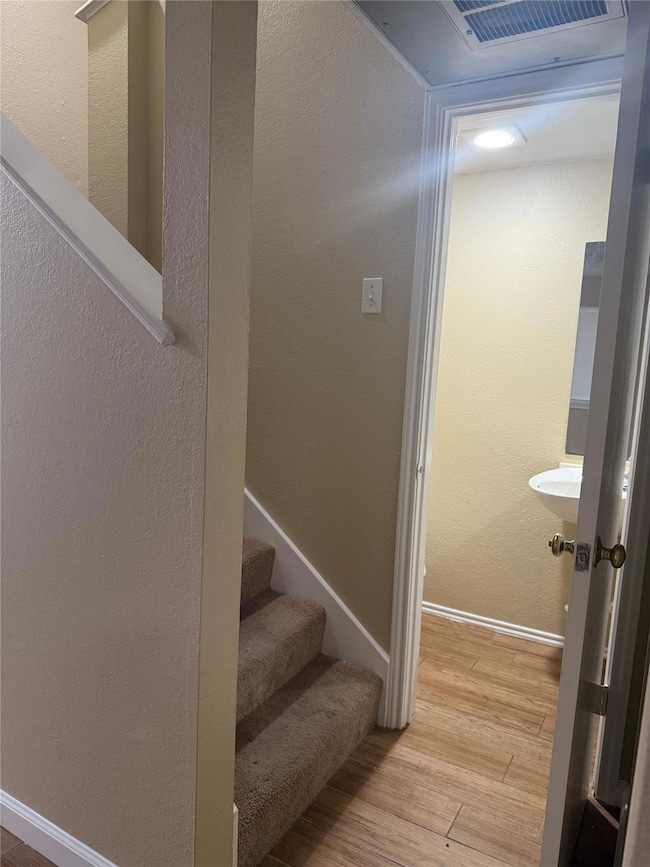 Stairway featuring a textured wall and wood finished floors