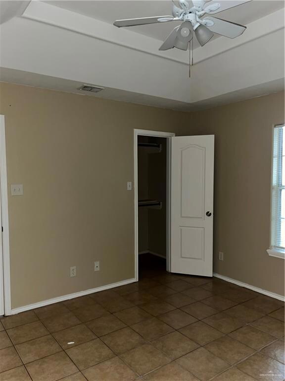 Spare room with tile patterned floors, a raised ceiling, baseboards, visible vents, and ceiling fan