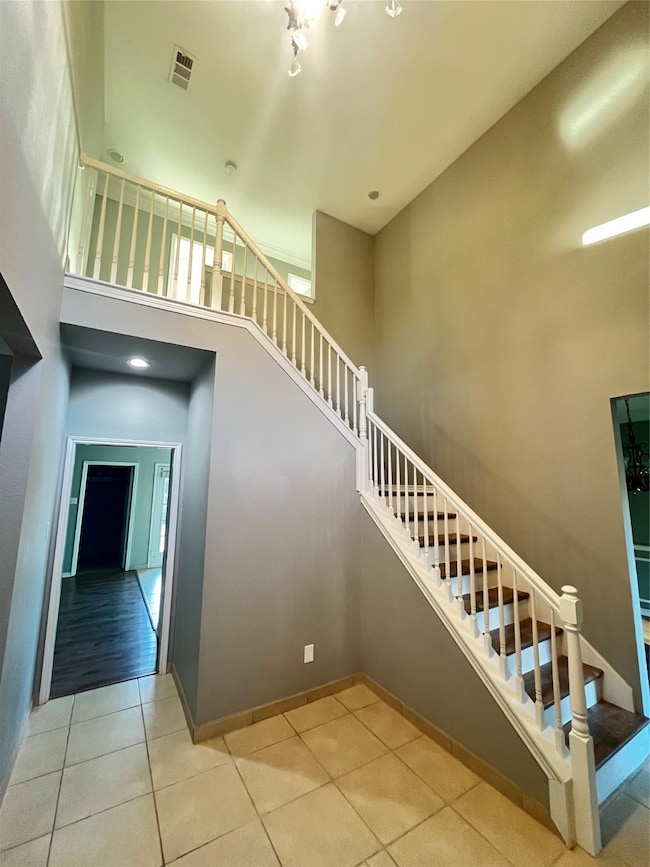 Stairs with a towering ceiling and tile patterned flooring