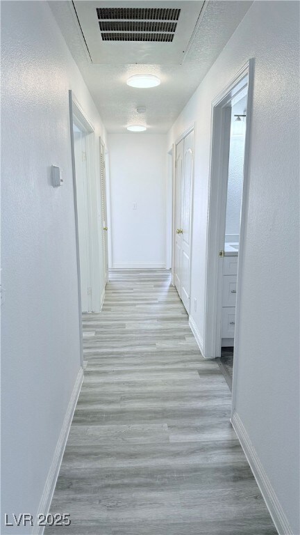 Corridor with wood finished floors, visible vents,