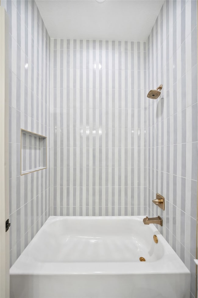 Full bath with tile walls and shower / washtub combination