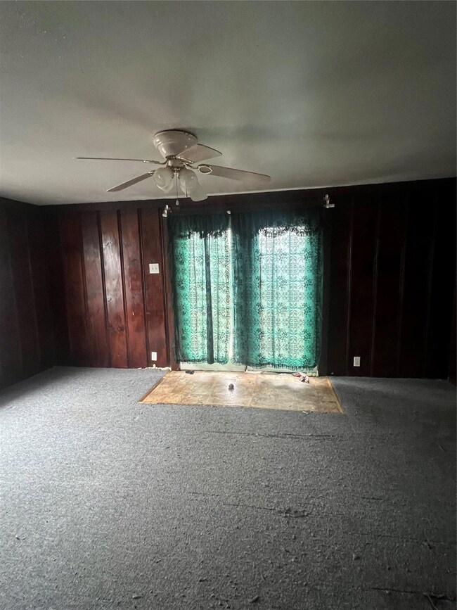Carpeted empty room featuring wooden walls and cei