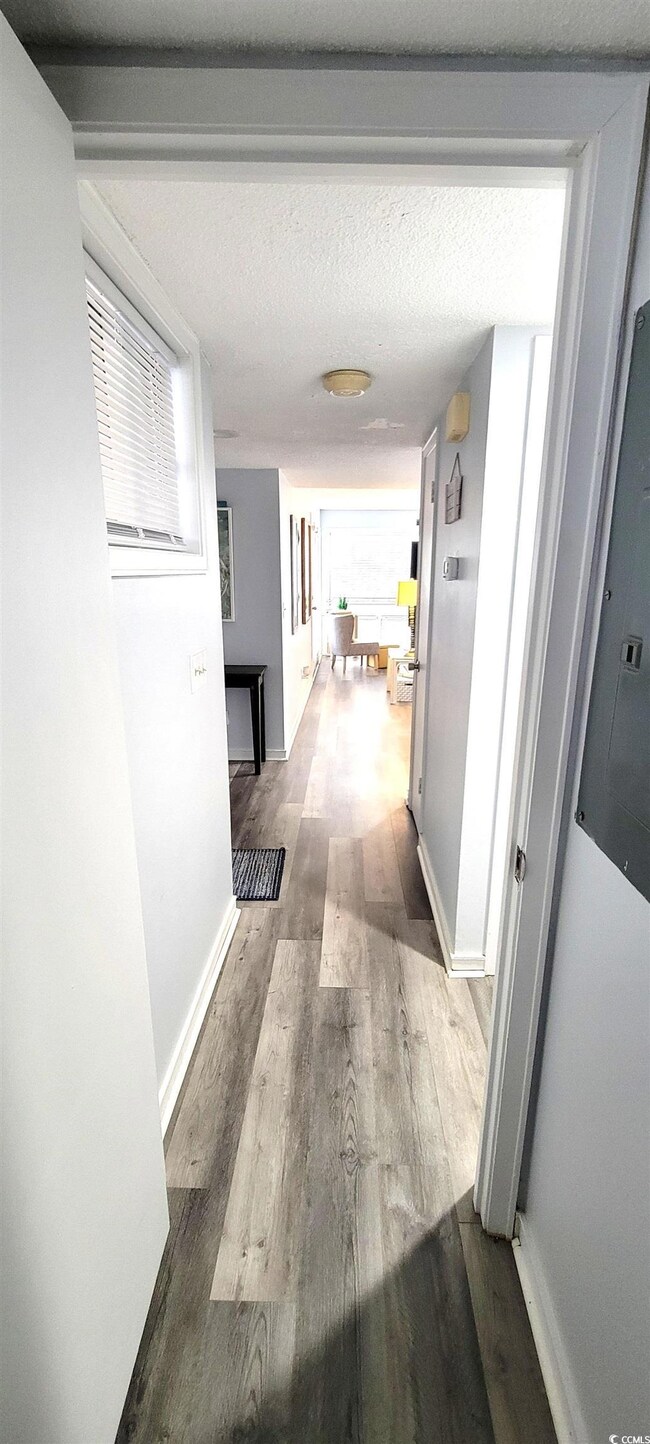 Hall with electric panel, a textured ceiling, base