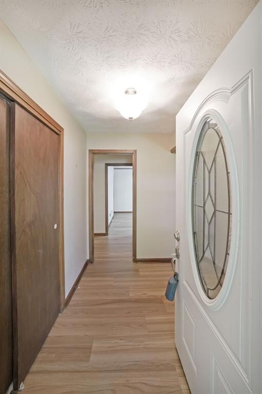 Corridor with light wood-style flooring and a textured ceiling