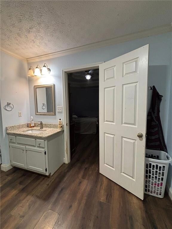 Bathroom featuring ornamental molding, vanity, dark wood-type flooring, a textured ceiling, and ensuite bath