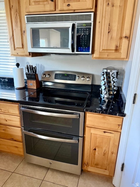 Kitchen featuring appliances with stainless steel finishes, light tile patterned flooring, and light brown cabinets