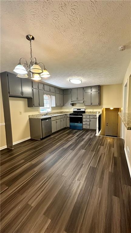 Kitchen featuring decorative light fixtures, a textured ceiling, dark wood finished floors, gray cabinets, and appliances with stainless steel finishes