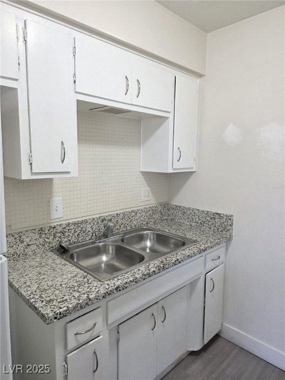 Kitchen with white cabinets, backsplash, and light