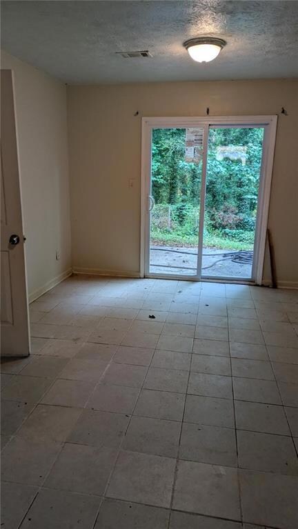 Spare room featuring a textured ceiling and light tile patterned flooring