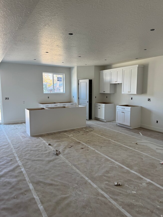 Kitchen featuring a textured ceiling, white cabinetry, and a kitchen island