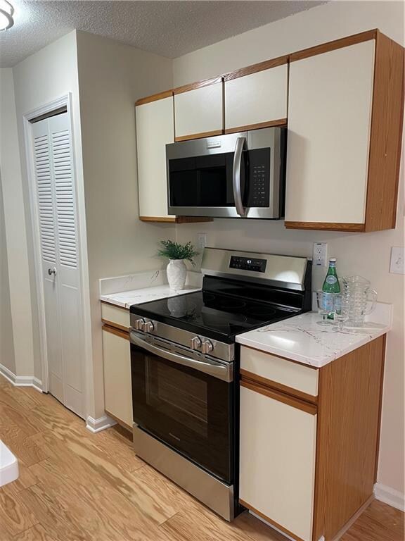 Kitchen with baseboards, white cabinetry, light wo